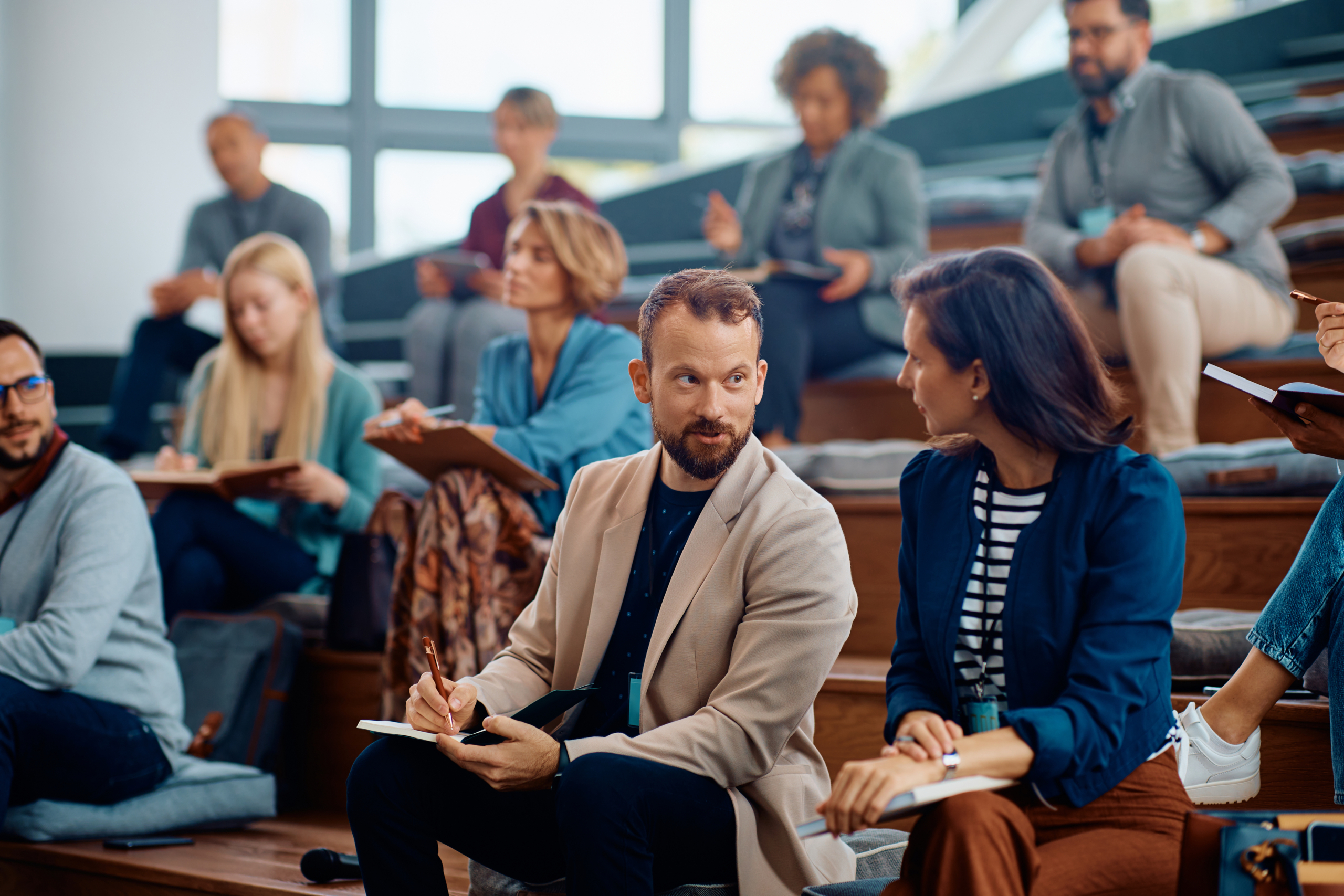 Business seminar attenders talking during a lecture in conference hall.